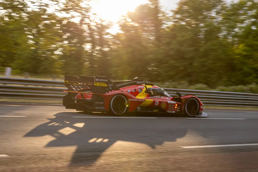 Une voiture de course filant sur le circuit au soleil couchant