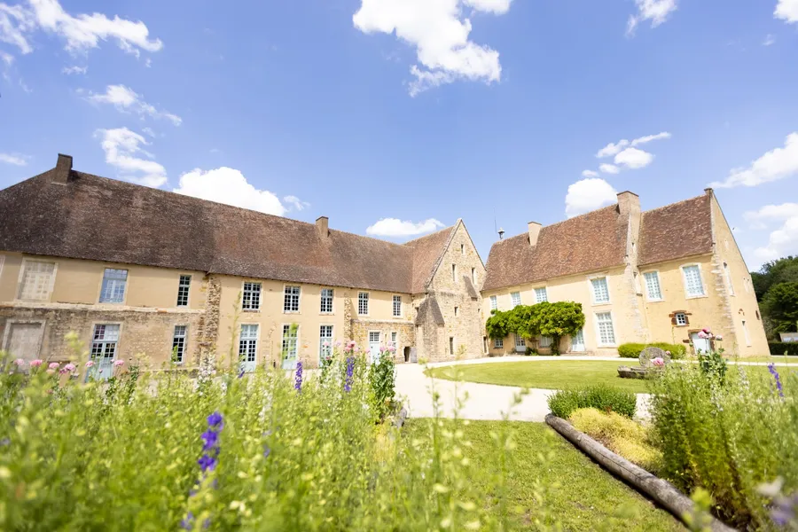Les bâtiments de l'abbaye de l'Épau derrière un massif de fleurs