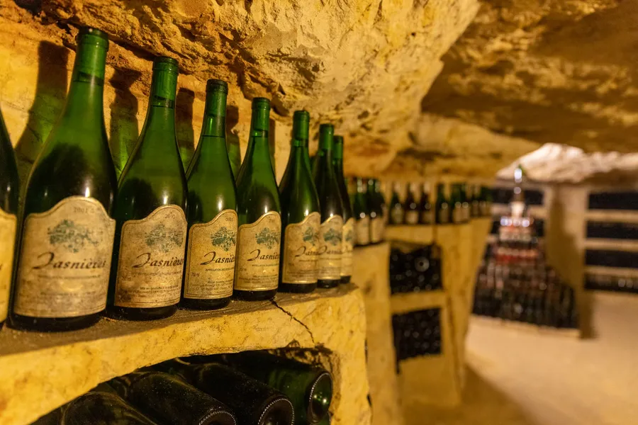Des bouteilles de Jasnières alignées dans une cave creusée dans le tuffeau